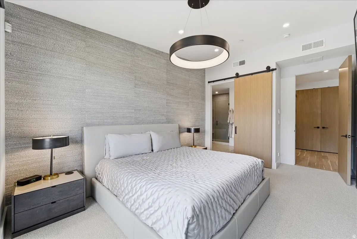 Bedroom with a barn door, light carpet, and recessed lighting