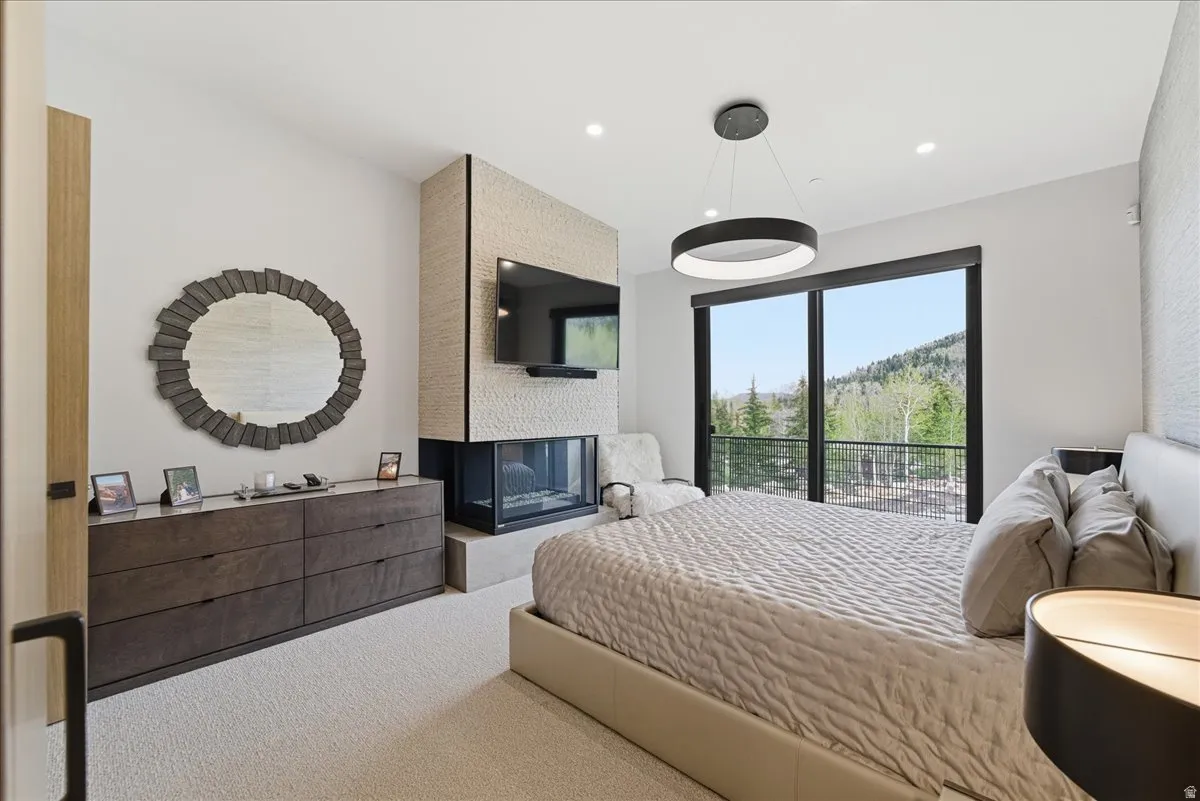 Carpeted bedroom with recessed lighting and a multi sided fireplace