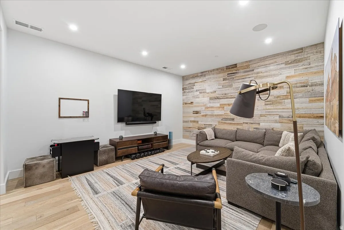 Living room featuring an accent wall, wood walls, recessed lighting, and light wood-style flooring