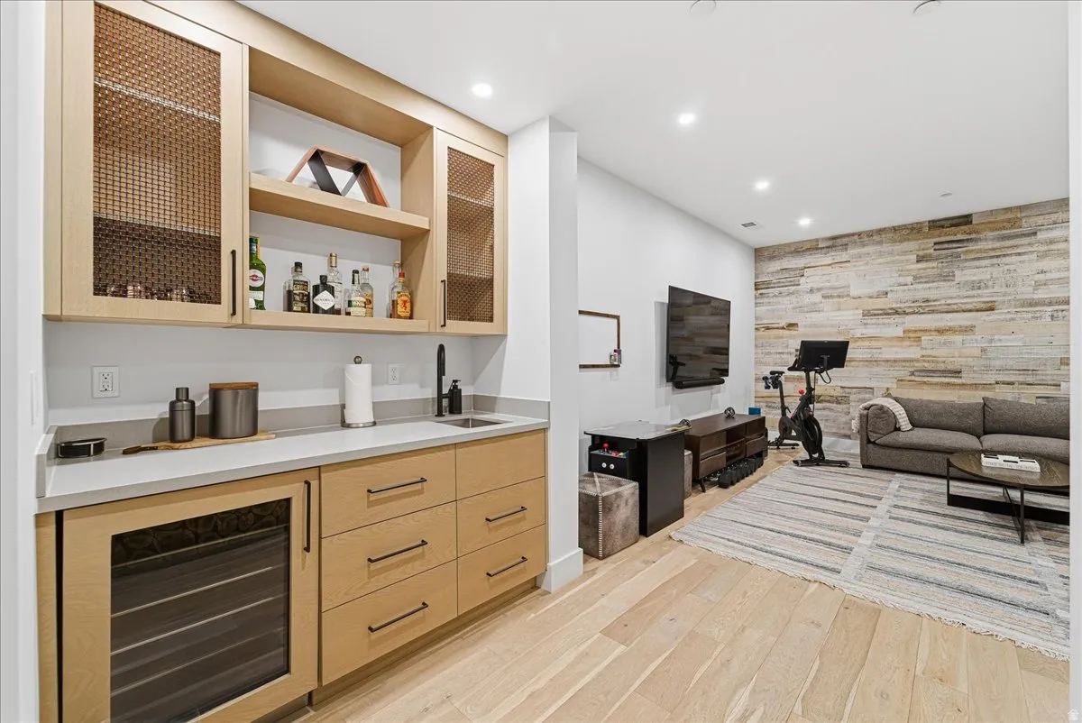 Indoor wet bar with an accent wall, glass insert cabinets, wine cooler, light wood-style floors, and recessed lighting