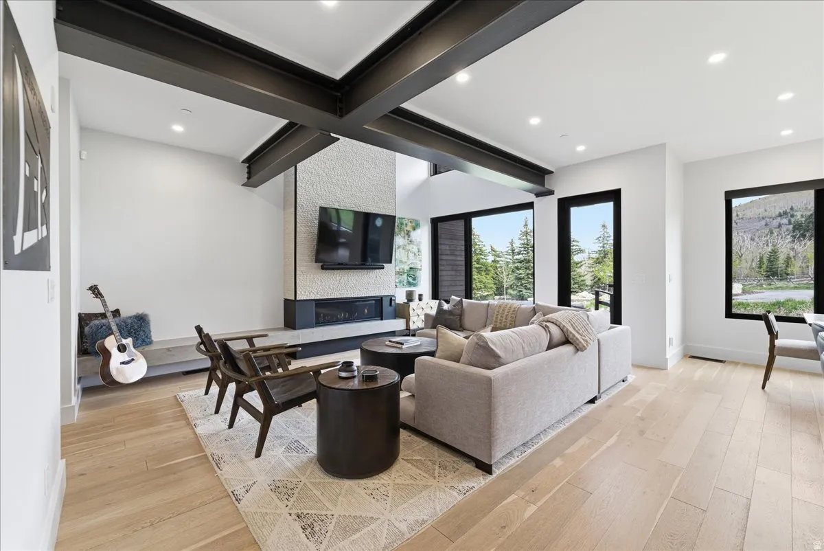 Living room featuring light wood-style floors, a large fireplace, beam ceiling, and recessed lighting