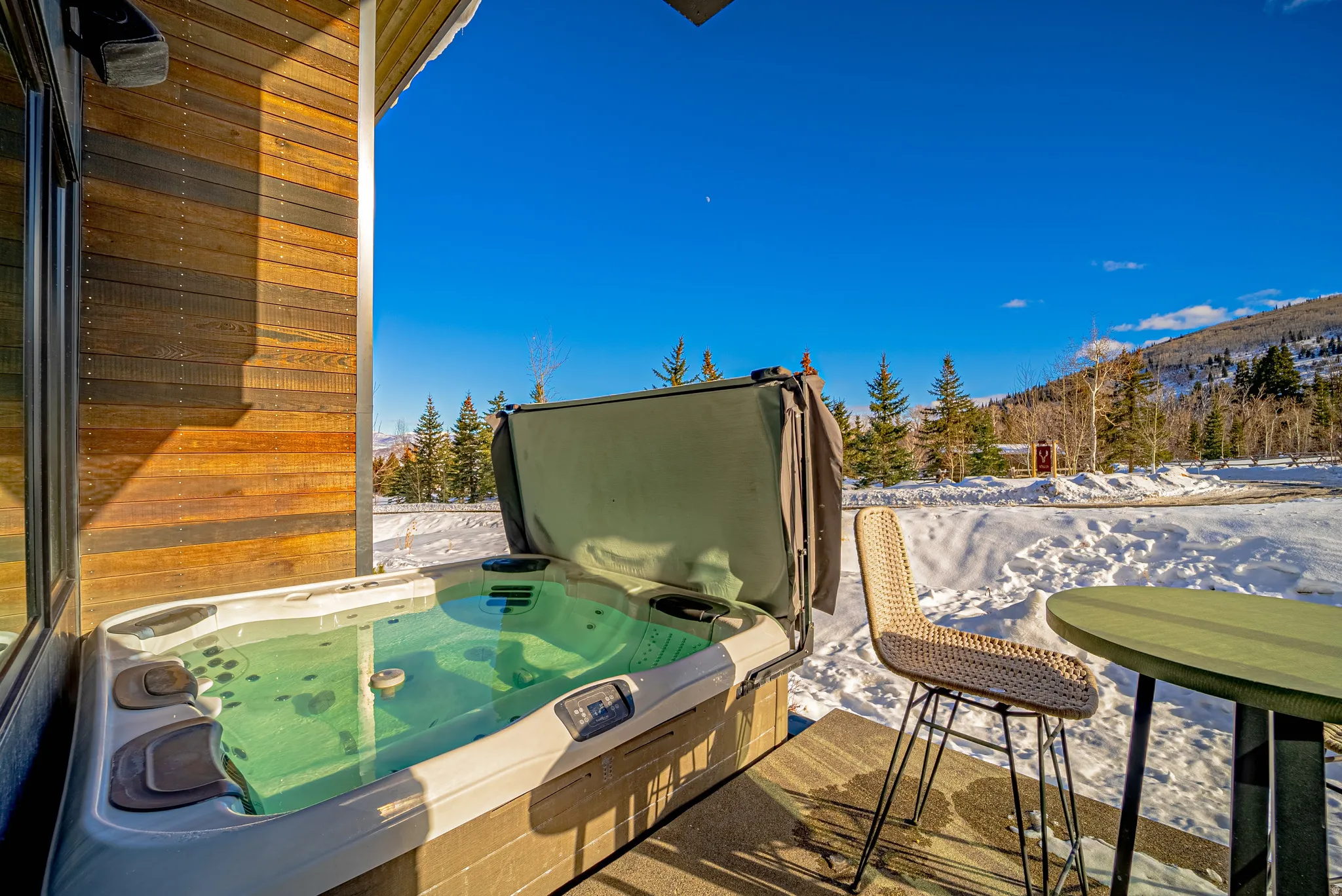 Snow covered deck featuring a hot tub and a mountain view