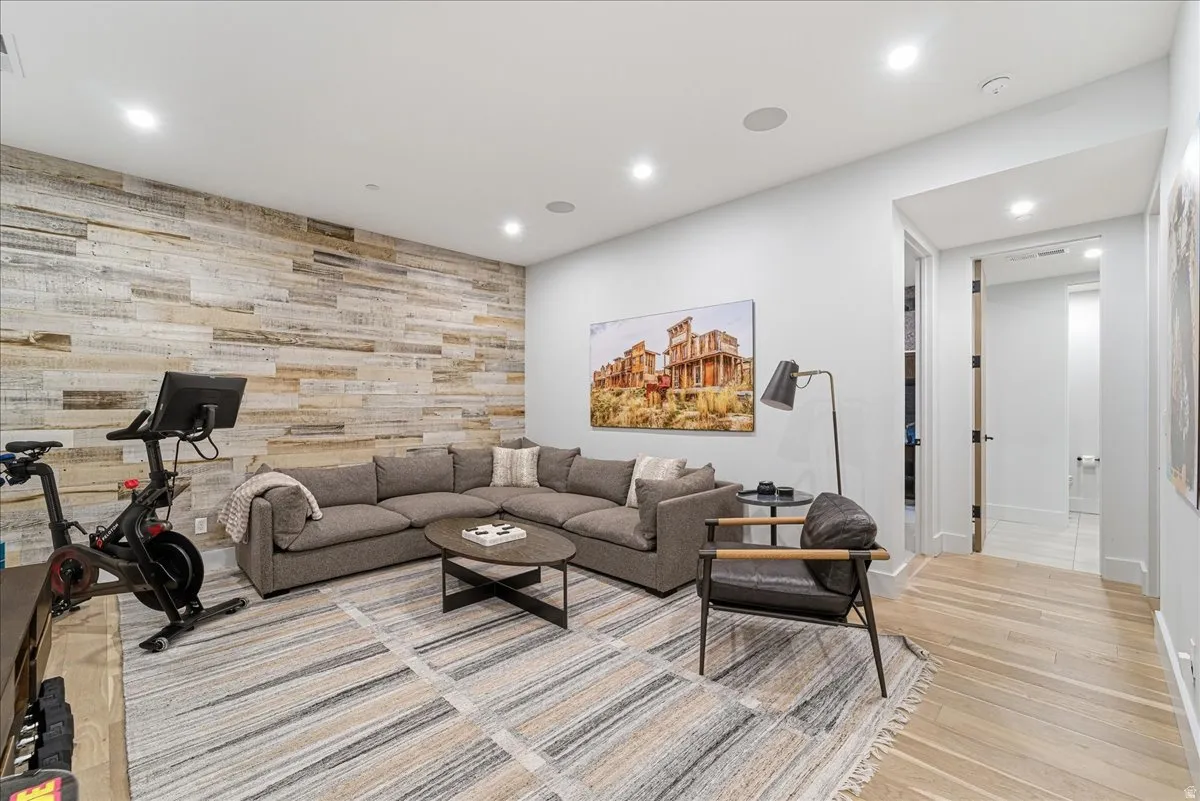 Living room with an accent wall, wood walls, recessed lighting, and light wood-style flooring