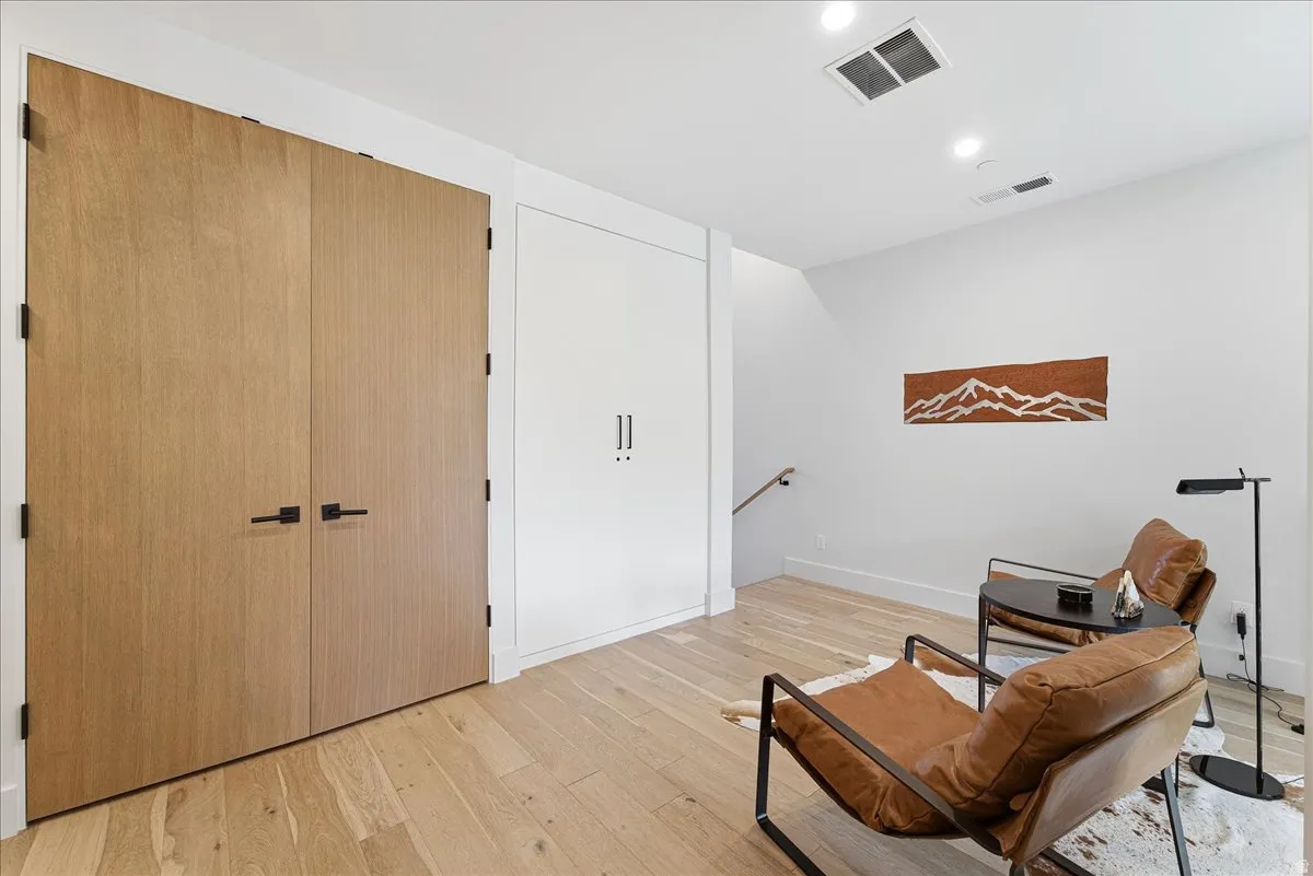 Sitting room with an upstairs landing, light wood-type flooring, and recessed lighting