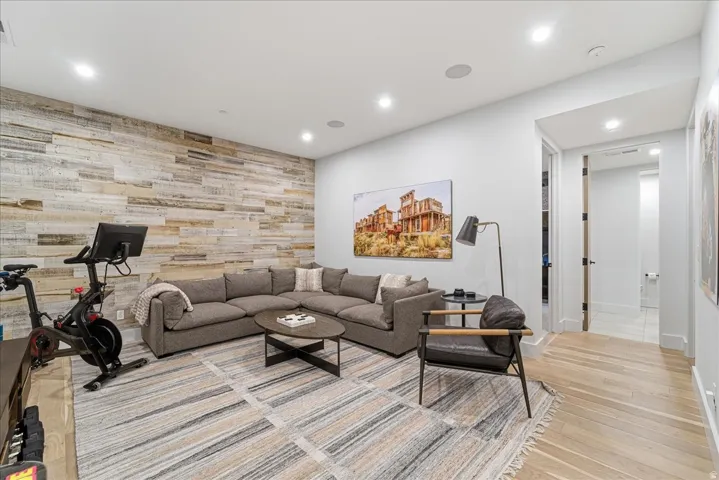 Living room with an accent wall, wood walls, recessed lighting, and light wood-style flooring