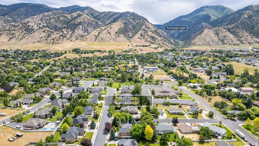 Residential neighborhood with paved streets and mature trees, set against a backdrop of mountainous terrain