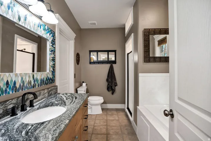 Bathroom featuring a wood-finish vanity with an undermount sink and a patterned stone countertop