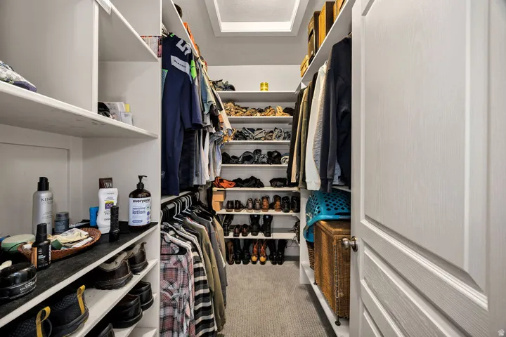 Walk-in closet featuring built-in shelving, hanging rods, carpet flooring, and recessed ceiling lighting