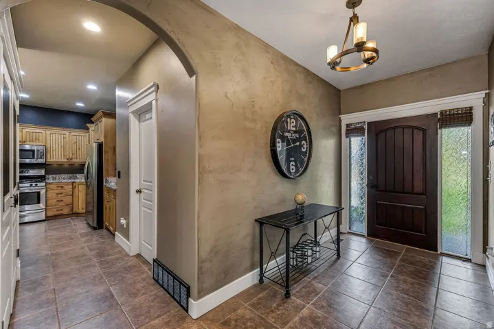Entryway featuring a dark wood arched-top front door, frosted sidelight windows, and tile flooring