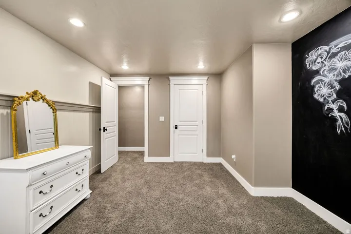 Carpeted room featuring recessed lighting, a chalkboard wall, white paneled doors, and wainscoting with a chair rail