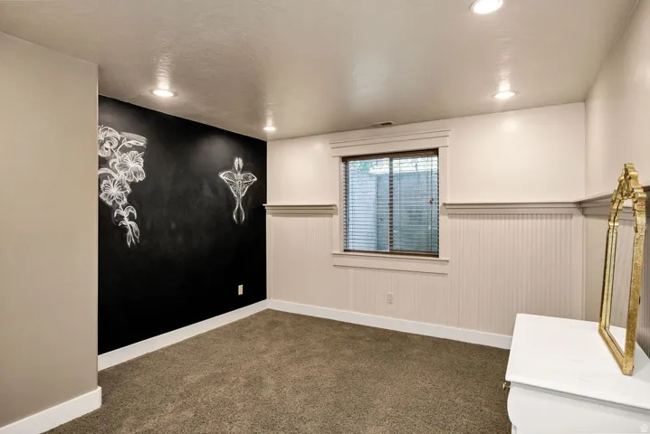 Carpeted room featuring a blackboard accent wall, recessed ceiling lighting, and a window with blinds