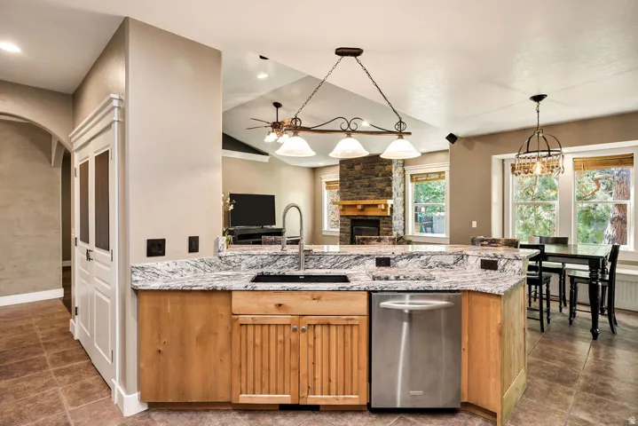 Kitchen island featuring a stainless steel sink, gooseneck faucet, light wood cabinetry, and a granite countertop