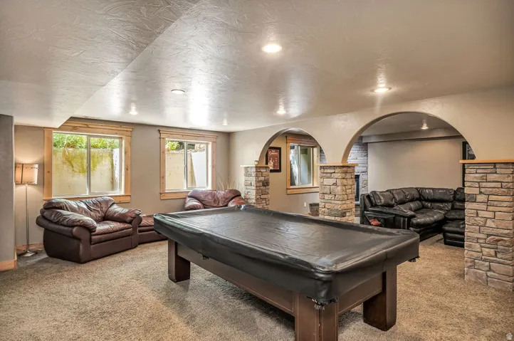 Lower level featuring arched doorways, stone-clad columns, recessed lighting, and a neutral carpet