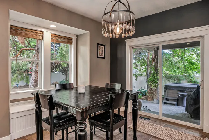 Dining area with a unique chandelier, dual windows featuring natural light, a window bench with beadboard detailing, and direct access to outdoor space via sliding glass doors