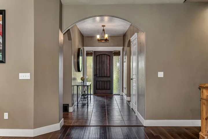 Arched entryway with dark wood-finish flooring transitioning to large format tile