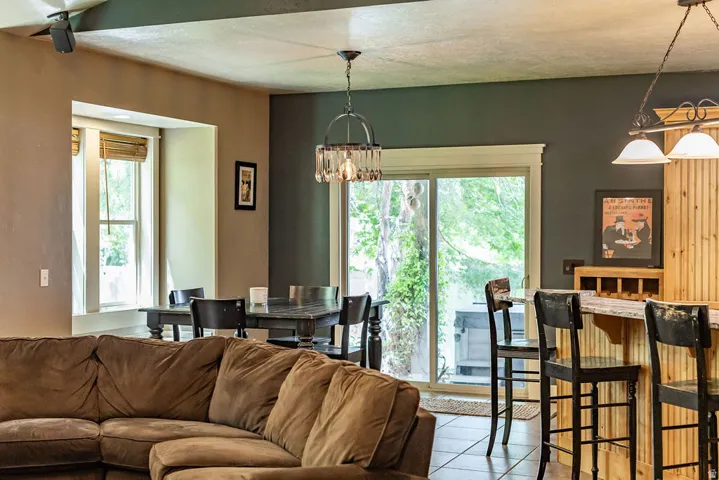 Open concept living area featuring a sliding glass door, a built-in bar with wood paneling, a dining area with a window, and recessed lighting