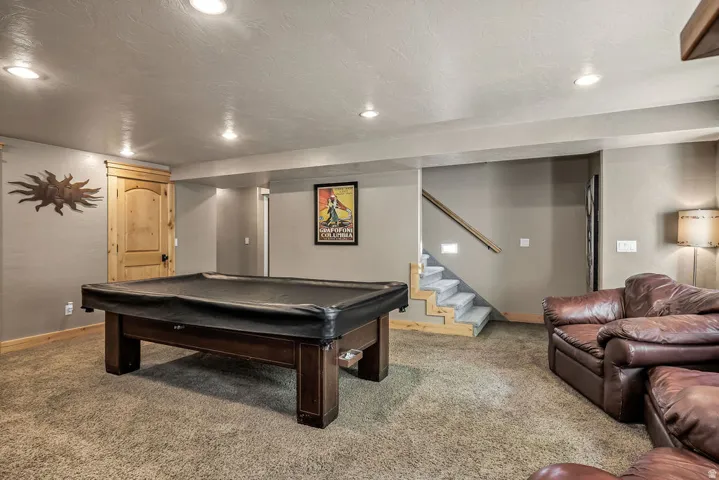 Spacious recreation room featuring carpet flooring, recessed lighting, and a wood-finish door