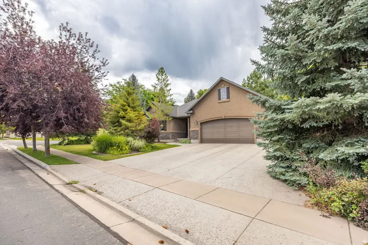 Exterior featuring a textured stucco finish, an arched two-car garage, and a peaked roofline