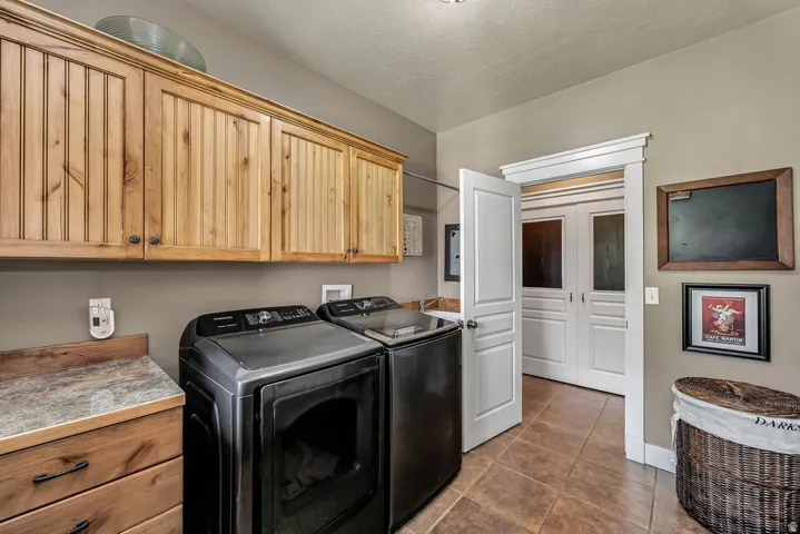 Laundry area featuring wood-finish cabinetry, a coordinating wood-finish countertop, and tiled flooring