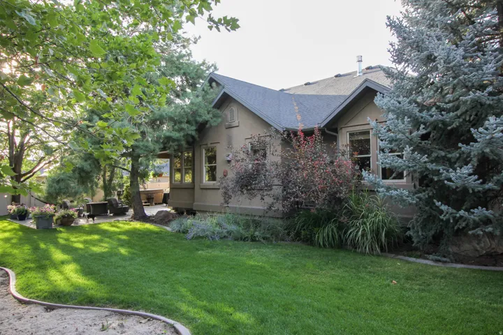View of home's exterior featuring a lawn, stucco siding, outdoor furniture, and roof with shingles
