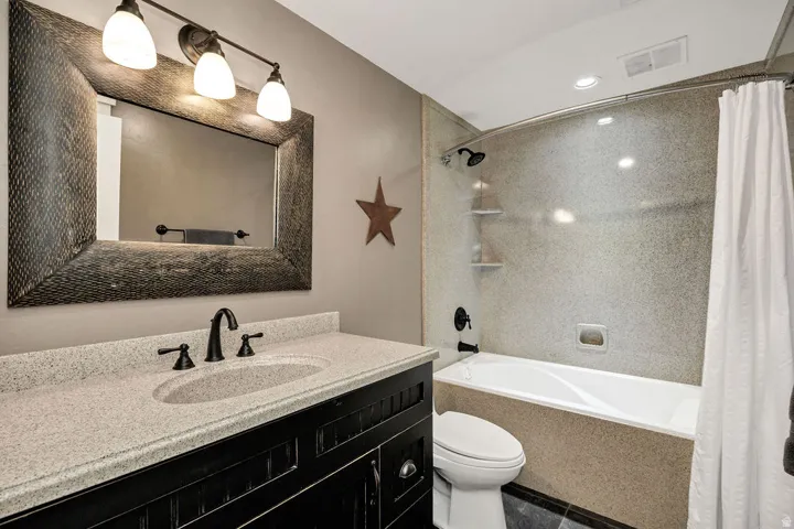 Vanity with an integrated sink, speckled countertop, and dark cabinetry