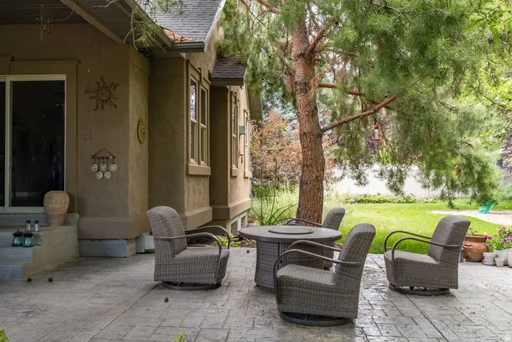 Stamped concrete patio featuring a mature tree, adjacent to a stucco exterior with multiple windows and a sliding glass door