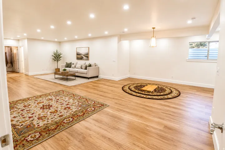 Spacious room featuring wood-finish flooring, recessed lighting, and crisp white walls