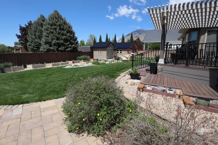 Expansive backyard featuring a manicured lawn, a privacy fence, and mature trees