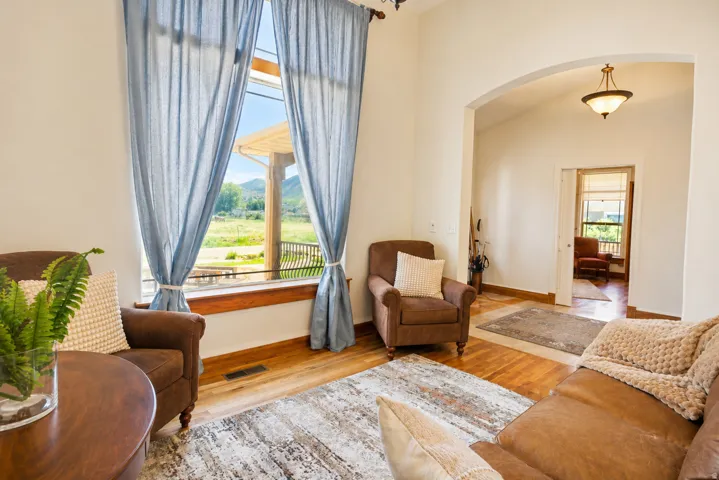 Living area featuring a large picture window with mountain scenery, wood-finish flooring, a vaulted ceiling, an arched entryway, and a semi-flush mount ceiling light fixture
