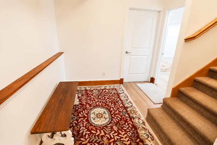Carpeted staircase with light wood handrail