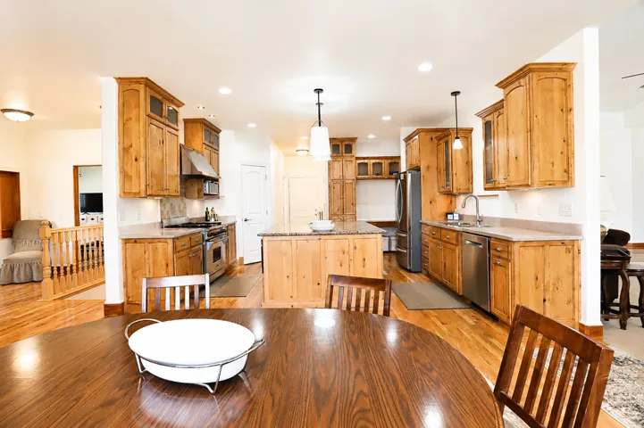 Spacious kitchen featuring wood-finish cabinetry, stainless steel appliances, a central island with a countertop, recessed lighting, and wood-finish flooring