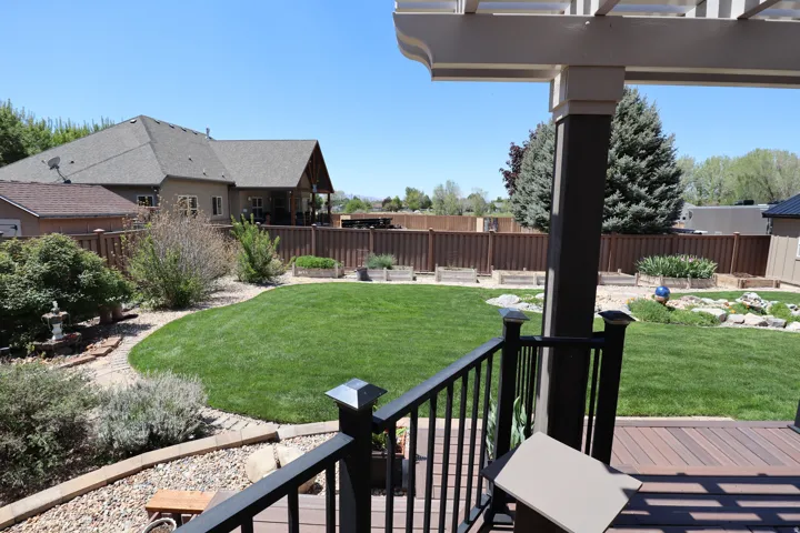 Expansive backyard featuring a manicured lawn, established landscaping, and a privacy fence