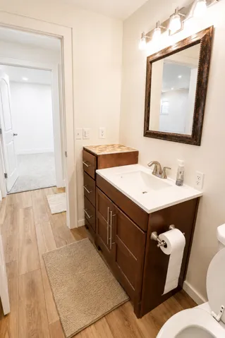 Bathroom featuring wood-finish flooring and a dark wood vanity with a white countertop and integrated sink