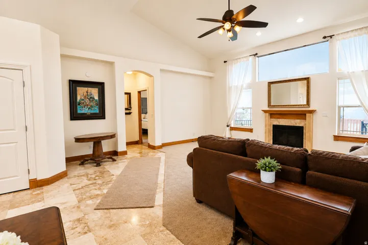 Vaulted ceilings and expansive windows frame the living area, featuring a fireplace with a stone surround and wood mantel
