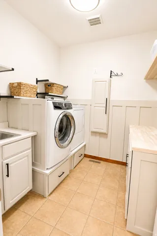 Dedicated laundry room featuring tile flooring, white shaker cabinetry, a utility sink, a butcher block style countertop, and board and batten wall detailing