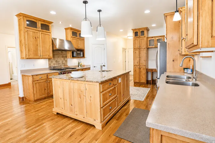 Spacious kitchen featuring warm wood cabinetry, granite countertops, and wood-finish flooring
