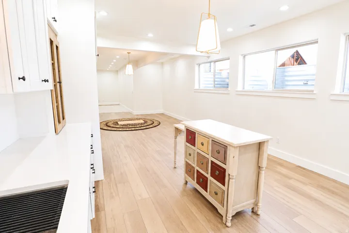 Recessed lighting illuminates an expansive room featuring wood-finish flooring and multiple windows