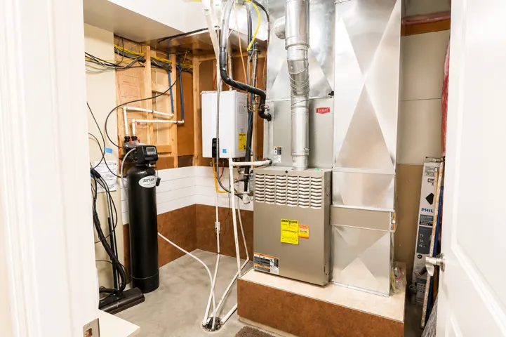 Utility area featuring a water softener, tankless water heater, and forced-air furnace