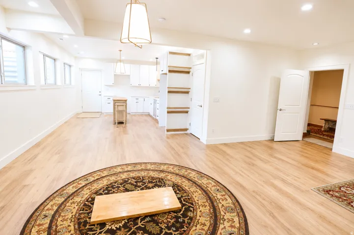 Open-concept living space featuring wood-finish flooring, recessed lighting, and a kitchen area with white cabinetry