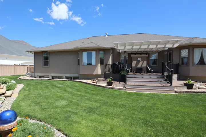 Expansive green lawn with a multi-level deck featuring a white pergola