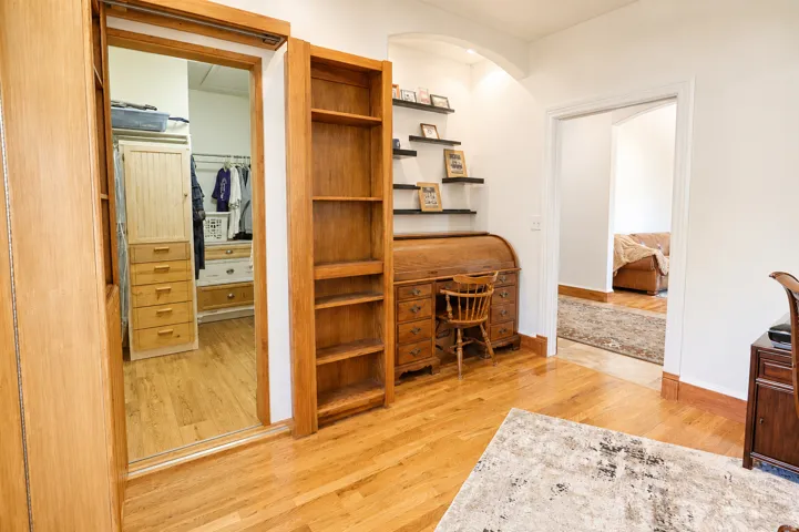 Hardwood flooring throughout featuring white walls and a white archway