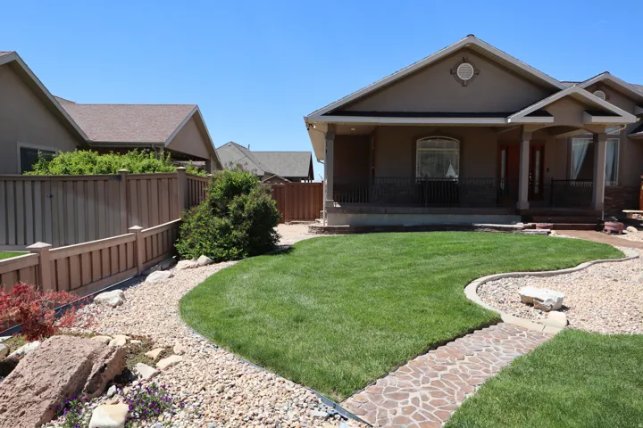 Stucco exterior with stone accents and a covered front porch featuring wrought iron railing