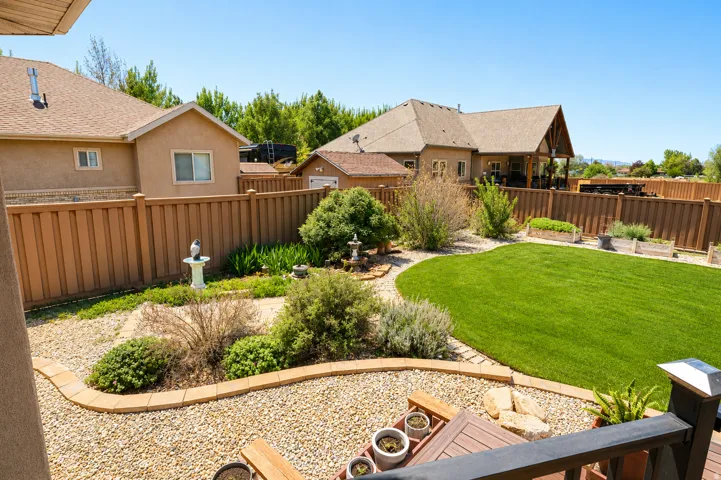 Spacious backyard featuring a manicured lawn, established landscaping, and decorative rock pathways