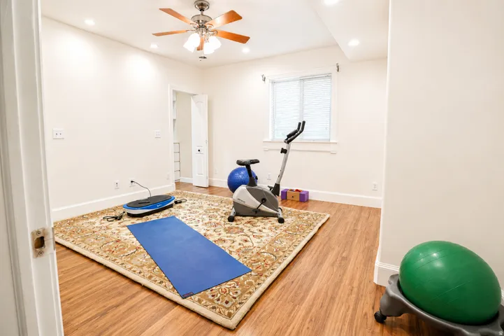 Spacious room featuring wood-finish flooring, recessed lighting, and a ceiling fan