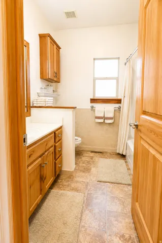 Bathroom featuring a wood-finish vanity with white countertop, integrated sink, and upper cabinetry