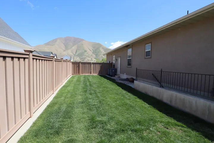 Expansive green lawn bounded by a privacy fence and a stucco exterior