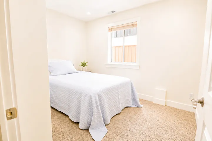 Bright room featuring neutral-toned carpet, a window with a wood-finish blind, white trim, and a recessed ceiling light