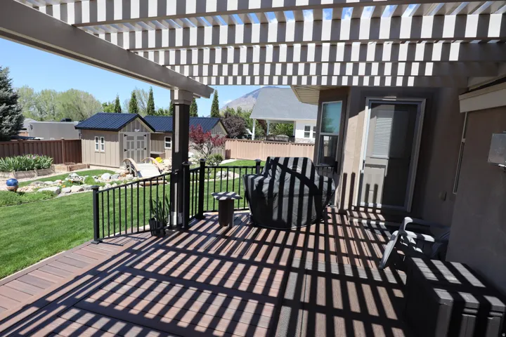 Expansive outdoor deck featuring wood-finish composite decking and a white slatted pergola
