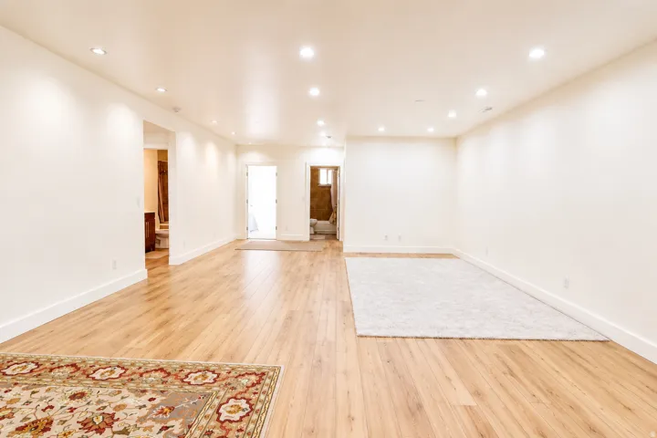 Spacious room featuring wood-finish flooring, recessed lighting, and bright white walls