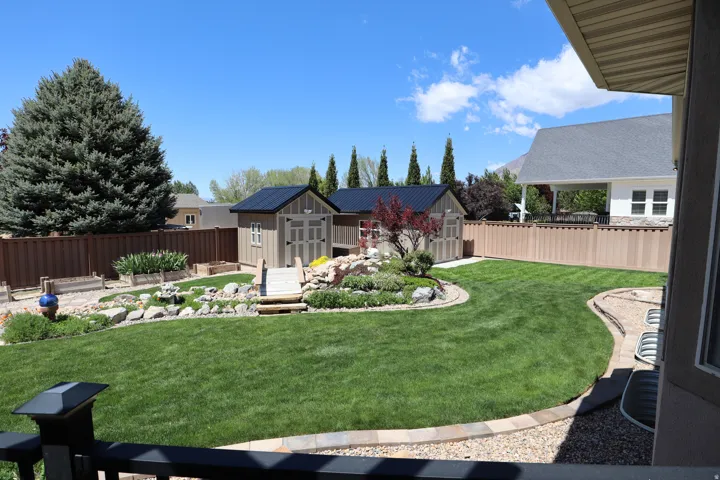 Expansive backyard featuring a manicured lawn, terraced rock gardens, and a built-in play structure